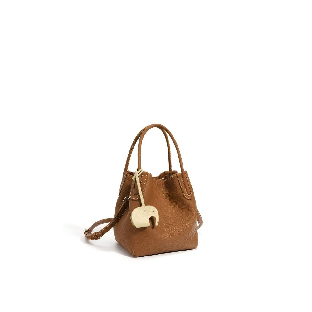 Brown handbag with a decorative elephant charm on a white background