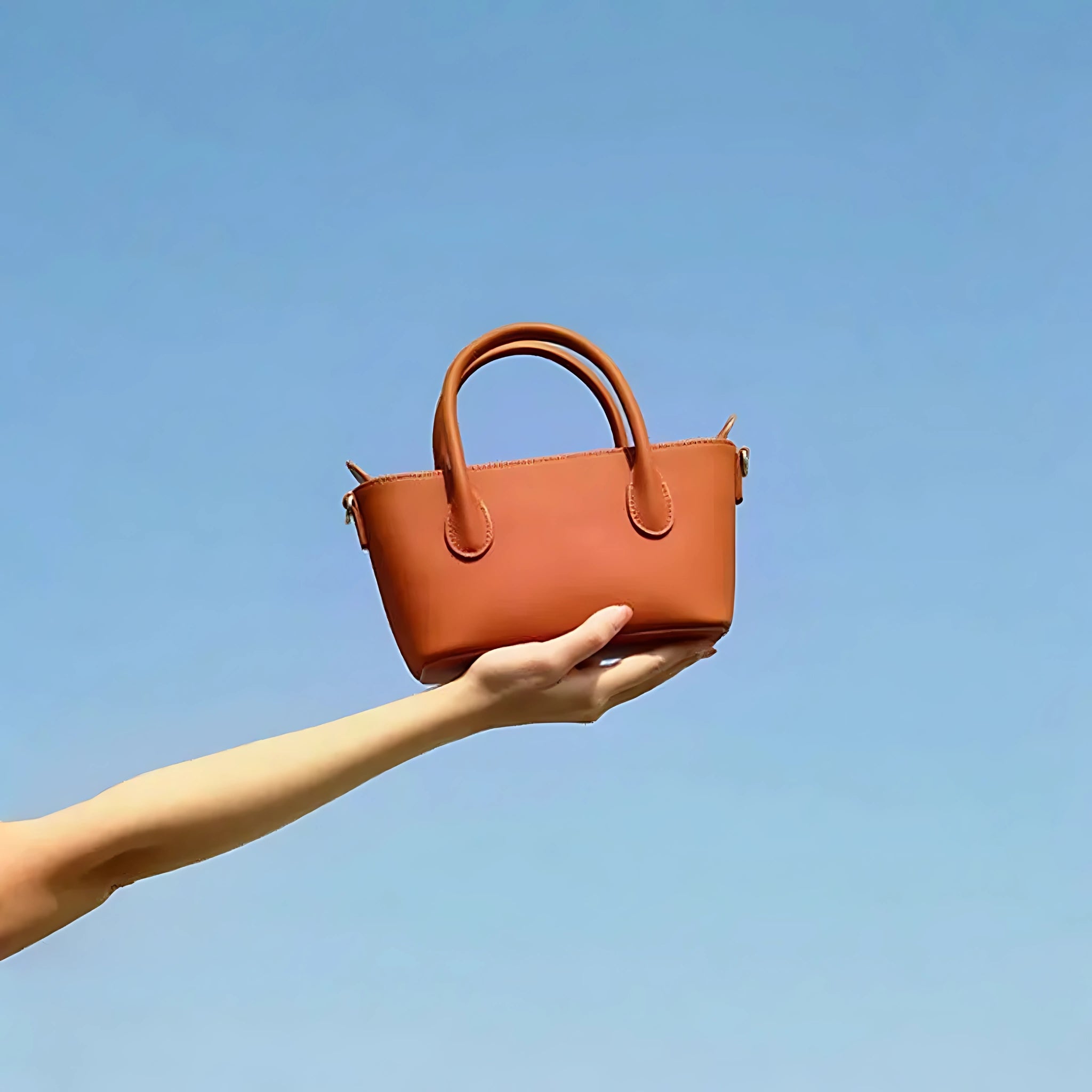 Hand holding Bagulia Minnie topgrain leather bag front view – refined craftsmanship, sleek minimalist design, luxury fashion accessory.