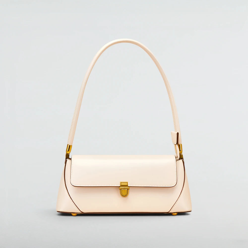 A light cream-colored leather shoulder bag with a single top handle and a gold-tone turn-lock clasp on the front flap, set against a solid light gray background. Laura Baguette Shoulder Bag - Bagulia