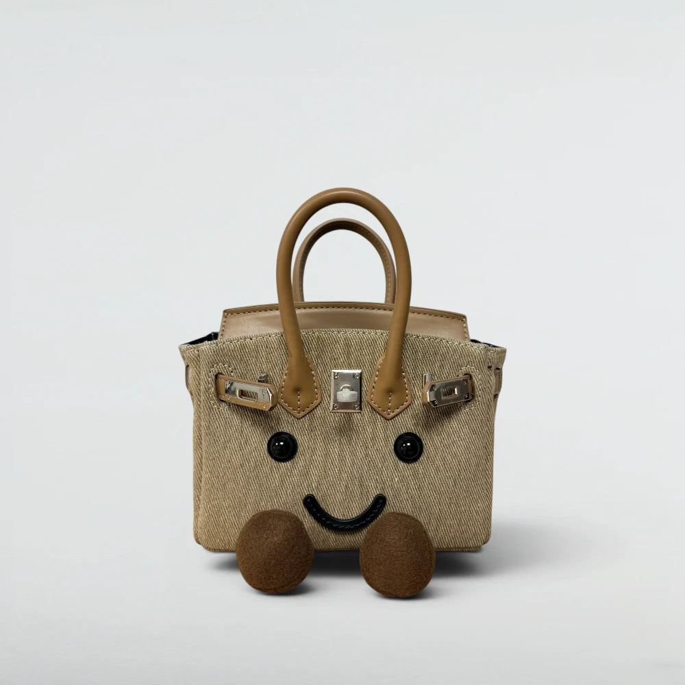 Bagulia Birky 18cm mini twill Birkin-style bag in Sand Twill with camel leather handles and smiley face, front view