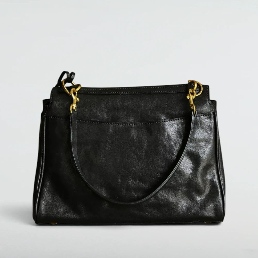 A black leather shoulder bag with gold-tone hardware, shown against a plain light gray background.