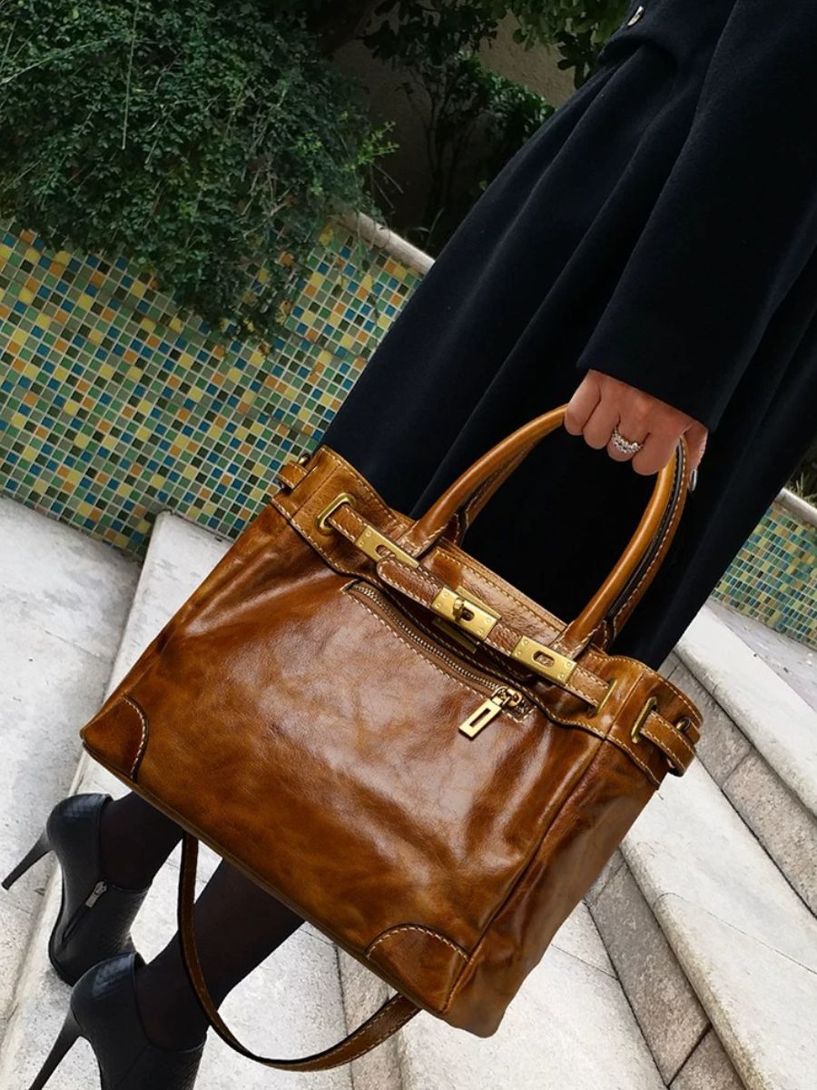 Woman carrying the Bagulia Petra Glossy Leather Tote Bag in Caramel, close-up detail